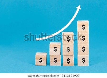 Image of wooden blocks with dollar signs stacked in increasing order, representing financial growth, with an upward arrow drawn on a blue background.