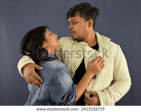 Affectionate couple embracing and looking at each other against a grey background