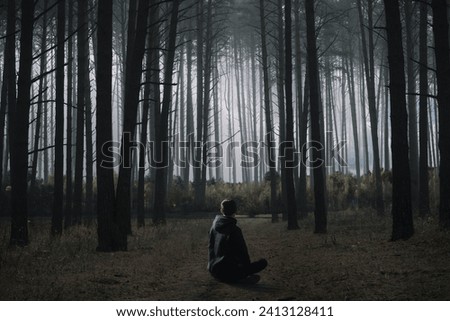 A young man is sitting on a forest path. High pine forest and dense grove, multi-exposure photography