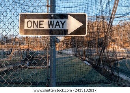 One way sign on a metal fence.