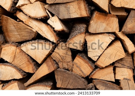 Background chopped firewood is lying in a pile stock a wall of wood preparing for winter