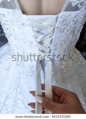 white satin dress for a wedding, lacing on a dress, engagement, wedding, fabric, lace, veil, tailoring, manicure, dressing a dress, groomsman for a wedding, assistant for a wedding, Royalty-Free Stock Photo #2413155305