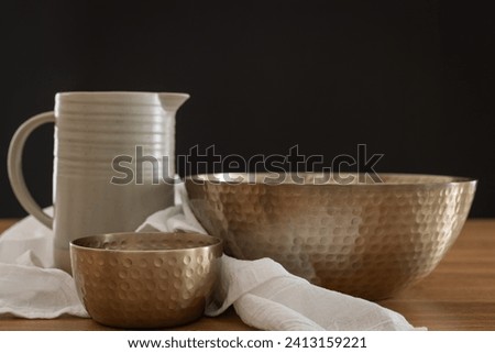 Clay pitcher, two copper bowls and white linen with a black background and copy space Royalty-Free Stock Photo #2413159221