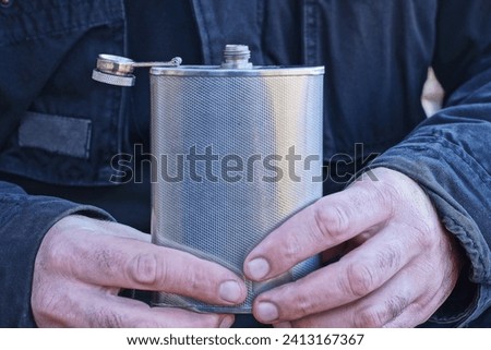 hands hold one white metal flask on a black background