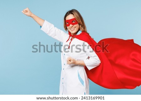 Side profile view female happy doctor man wear white medical gown suit red super hero coat mask work in hospital do fly gesture isolated on plain blue background studio. Healthcare medicine concept
