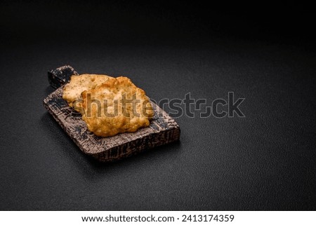 Delicious juicy fried chicken or pork pancakes with salt, spices and herbs on a dark concrete background
