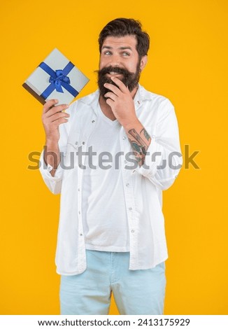 smiling caucasian birthday man with purchase isolated on yellow. birthday man with purchase