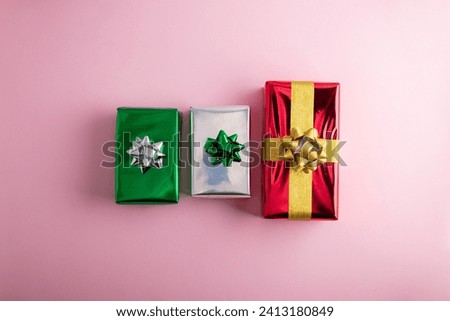 Creative handmade christmas green, red and silver shiny gift boxes with decor on pastel pink background, top view
