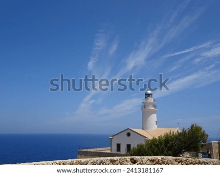 Lighthouse on the shores of the blue Mediterranean Sea on the beautiful island of Palma de Mayorca, blue sky, horizontal photo.