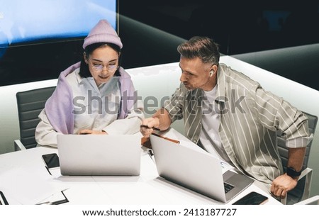 Diverse male and female in eyewear and headphones checking received email message on modern laptop, skilled IT professionals creating startup projects during brainstorming cooperation in office