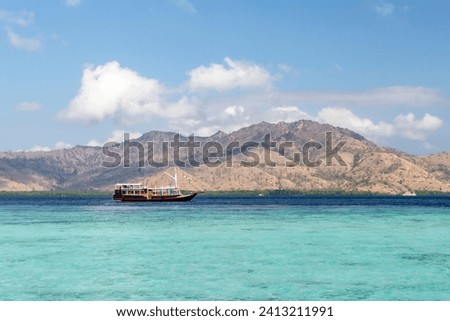 Panorama view of beaches and tourist boat sailing in Taka Makasar Island, Flores Island, Indonesia
