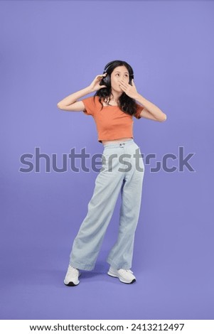 Full body smiling asian cheerful young adult woman enjoy carefree music headphone freedom lifestyle,casual cloth asia woman hand gesture happiness photo studio shoot on purple colour background