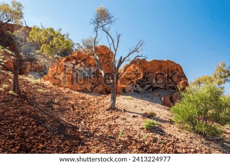 A mesa rock formation with small caves in its escarpments locally known as "Cave Hill" in the Australian outback Royalty-Free Stock Photo #2413224977