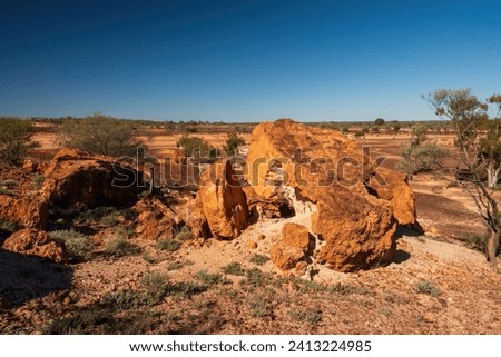 A mesa rock formation with small caves in its escarpments locally known as "Cave Hill" in the Australian outback Royalty-Free Stock Photo #2413224985