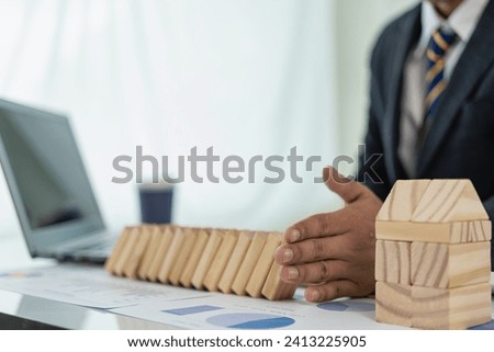 Businessman uses hands to block falling wooden blocks, controlling risk, planning and strategy in business. Alternative risk concept, risk creating business growth with wooden blocks, close-up image