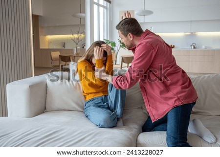 Abuser tyrant husband fighting wife screaming sitting on couch at home. Jealous man suspects woman of cheating. Toxic relationship, abuse, domestic physical emotional violence, manipulation scandal. Royalty-Free Stock Photo #2413228027