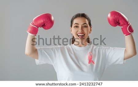 Woman in boxing gloves with a pink ribbon as a symbol of the fight against cancer. Increasing the level of knowledge about people who have overcome tumor diseases. Royalty-Free Stock Photo #2413232747
