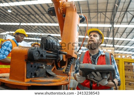 Factory engineer inspecting on machine. Workers work at heavy machine robot arm. The welding machine with a remote system in an industrial factory. smart industry worker operating. Wood factory.
