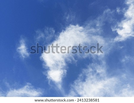 a landscape of clouds in a clear blue sky, looking like a flying dragon's head