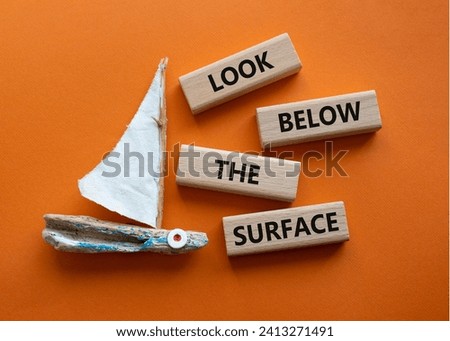 Look below the surface symbol. Concept word Look below the surface on wooden blocks. Beautiful orange background with boat. Business and Look below the surface concept. Copy space