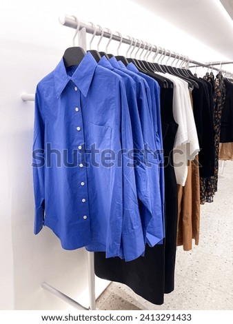 brightly colored sweater,dress ,shirt  hung on a hanger in a clothing store for sale 