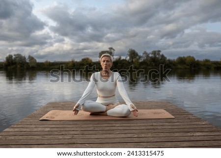An adult woman in a white suit is engaged in kundalini yoga, the practice of shitali pranayama, exercise tongue wrapped Royalty-Free Stock Photo #2413315475