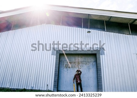 Indonesian Worker Man Standing In Front of Warehouse Rolling Door Wearing Hat, Red Flanner an Yellow Umbrella Sun Flare at Yogyakarta Indonesia