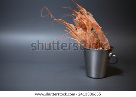 frozen pink queen shrimp in a bucket on a gray background
