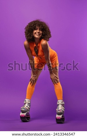 Beautiful sporty woman with curly hair wearing kangaroo jumper on studio background