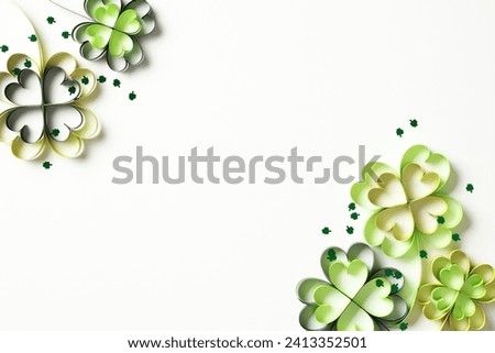 St. Patrick's day greeting card design. Flat lay composition with paper craft four leaf clover and confetti on white background.