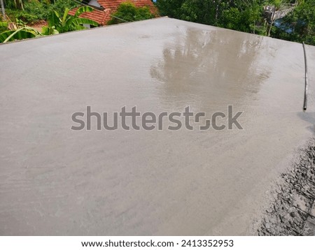 A portion of main slab concrete mix just finished leveling, with a pvc pipe.Hd stock photo taken immediately after concrete is done with lot of moisture on its surface, tied up steel seen on the side.