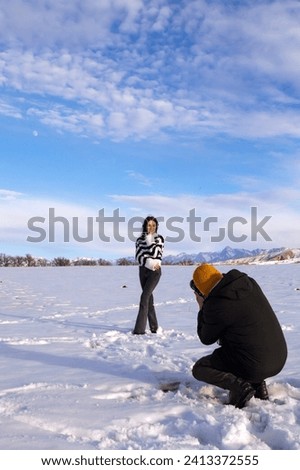 A young beautiful couple of tourists, a man and a woman, take photographs as a souvenir in the winter landscape.
