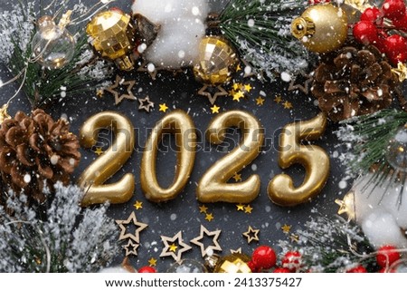 The golden figures 2025 made of candles on a black stone slate background are decorated with a festive decor of stars, sequins, fir branches, balls and garlands. Greeting card, happy New Year.