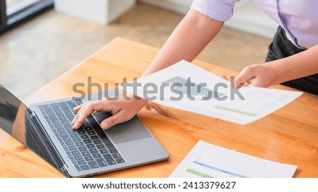 Businesswomen reading document and typing data on laptop while thinking about strategy of startup.
