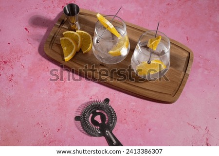 Picture of two gin tonics served in tumble glasses with orange slices as garnish captured in photographic studio