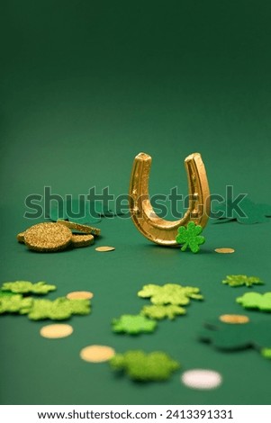 St Patricks day card with traditional symbols for irish party. Golden horseshoe, gold coins, clover leaves, green shamrocks on green background, copy space. St. Patrick's Day celebration concept. 