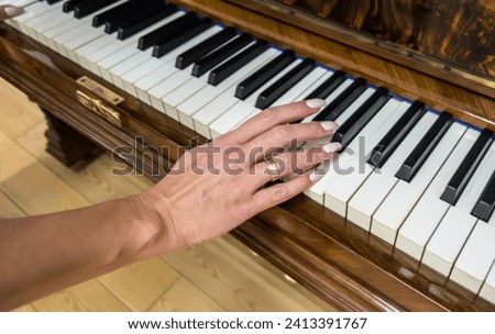 The hand of a young girl with a modern manicure touches the piano keys. The concept of music, entertainment, music education, choice of musical instruments.