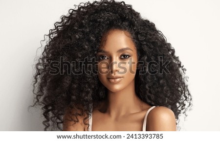 Beauty portrait of african american girl with clean healthy skin on beige background. Smiling dreamy beautiful black woman.Curly  hair in afro style  Royalty-Free Stock Photo #2413393785