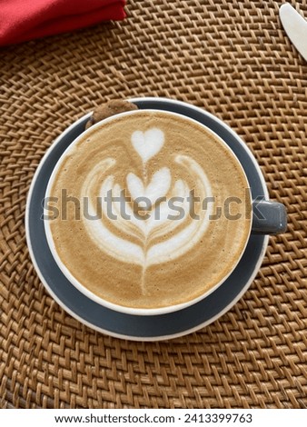 A cup of cappuccino coffee on the ornament table, with a picture of a leaf on it