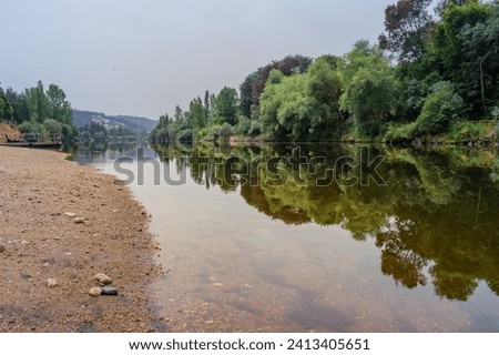 Reflection in the water of trees on the bank of the Mondego river at Reconquinho river beach in the morning, Penacova PORTUGAL Royalty-Free Stock Photo #2413405651