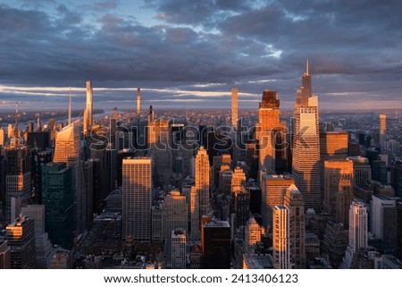 Midtown Manhattan supertall skyscrapers illuminated by warm light. Aerial view of New York City at sunset