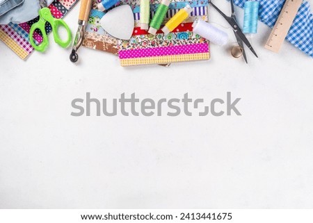 Sewing, needlework and clothing repair, background, scrapbooking, quilting. Colorful pieces of fabric, scissors, ruler, sewing tools, needles, threads on a white table background top view copy space Royalty-Free Stock Photo #2413441675