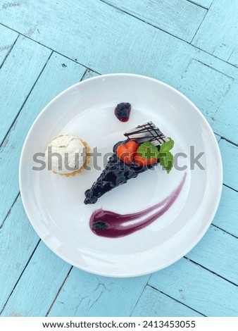 A picture of a dessert with the name of a chocolate cake served with vanilla ice cream and blueberry jam. Photographed by taking the top corner.