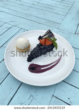 A picture of a dessert with the name of a chocolate cake served with vanilla ice cream and blueberry jam. Photographed by taking the top corner.