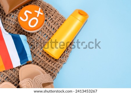 Summer composition sun protection product in yellow bottle with accessories on a blue background. 50 level sun protection for skin concept. Space for text. top view. High quality photo