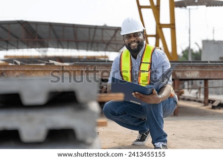 Man engineer with document checking quality concrete panels floor. Foreman wearing vest and helmet safety working in factory produce precast concrete, construction industry