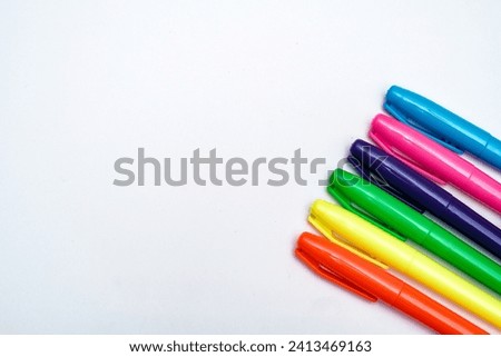 A group of coloured pens on a white surface