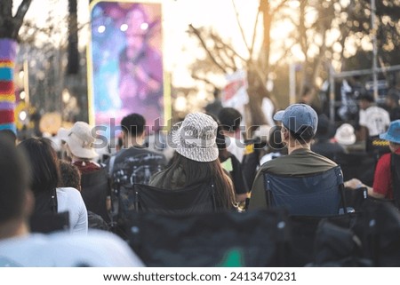 Couple watching concert in the park at open air music festival, back view Royalty-Free Stock Photo #2413470231