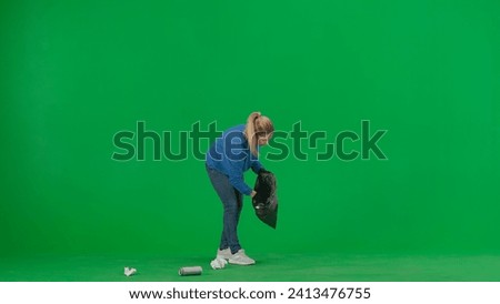 A female volunteer wearing black gloves and carrying a trash bag picks up trash on the green screen. Voluntary free work assistance help concept.