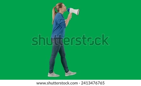 Female activist with raised fist shouting menacingly into megaphone in studio on green screen. Side view of a pro protest woman. Protest action, fight for women's rights, strike.
